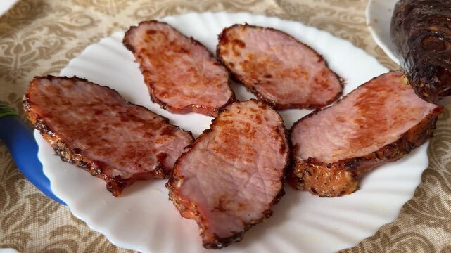 Fried pork steaks on plate, golden edges and crispy crust, arranged on white scalloped plate over patterned tablecloth, rustic