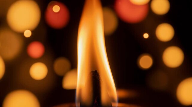 Burning flame of diya against blurred golden bokeh lights. Traditional oil lamp flickering during festival celebration. Spiritual ritual lighting for worship ceremony.
