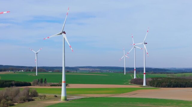 Wind turbines spin in open fields of Germany with blue sky above in this collection of four frames showing renewable energy in action