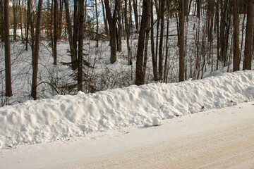 Obraz premium A plowed snowbank by the road in the winter forest