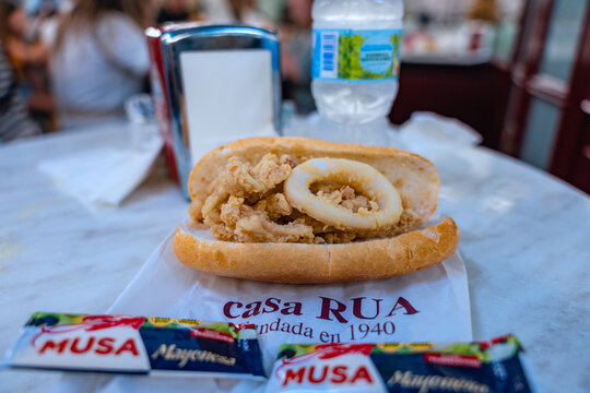 The tourist must-have traditional street food the golden, crunchy, fried, bocadillo de calamares squid sandwich in a crispy baguette, on a table of the famous Casa Rua restaurant in Madrid, Spain