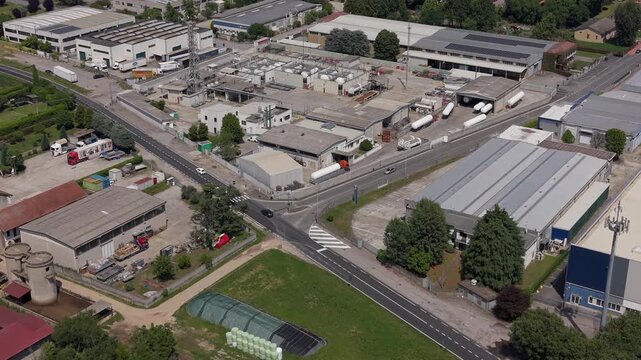 Aerial View of Industrial Park: An overhead shot captures a sprawling industrial park with multiple warehouses, factories, and transport vehicles, showcasing urban development and logistics