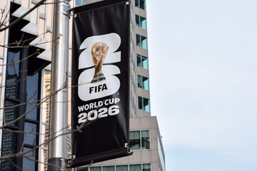 Fototapeta premium Closeup vertical banner promoting FIFA World Cup 2026 attached to street pole in urban downtown Toronto Ontario area with modern office buildings and copy space, May 17 2026