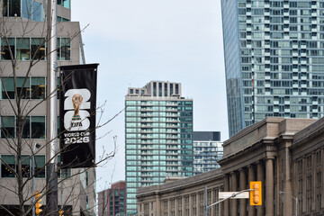 Fototapeta premium Vertical banner promoting FIFA World Cup 2026 attached to street pole in urban downtown Toronto Ontario area with modern office buildings and Union Station in the background, May 17 2026