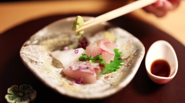 Chopsticks Mixing Wasabi into Soy Sauce Beside Fresh Sashimi Platter