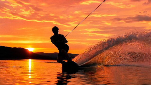 wakeboard. Wakeboarder carving water against a vibrant sunset sky. inspiring travel planning, event key visuals, designed for sports event promotions and stadium branding, used by event planners.