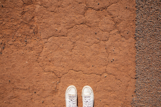 A journey begins. Anonymous white sneakers stand on arid red dirt in outback Australia