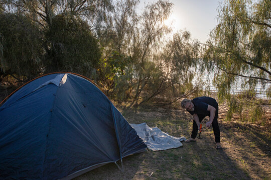 Man setting up a tent, camping near Lake Pamamaroo in the Australian Outback