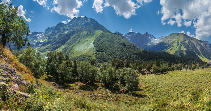 Valley in the Caucasus Mountains, rocky peaks, green slopes and blue sky