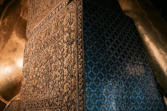 Detailed temple wall and golden Buddha statue in Bangkok
