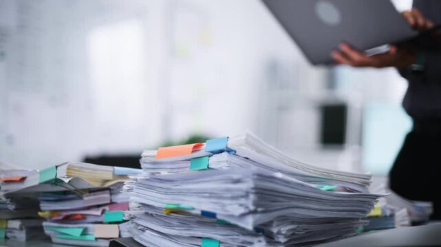 Close up document paperwork accounting financial working businessman management tax office report stacked on a desk while a businessman works in the background
