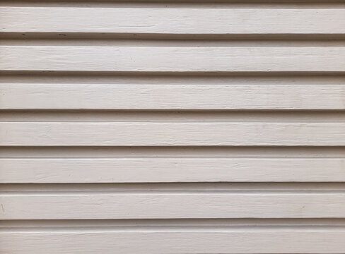 White concrete wall slats form neat, parallel rows. Soft lighting casts gentle shadows between each line. Texture shows subtle grain and natural wear
