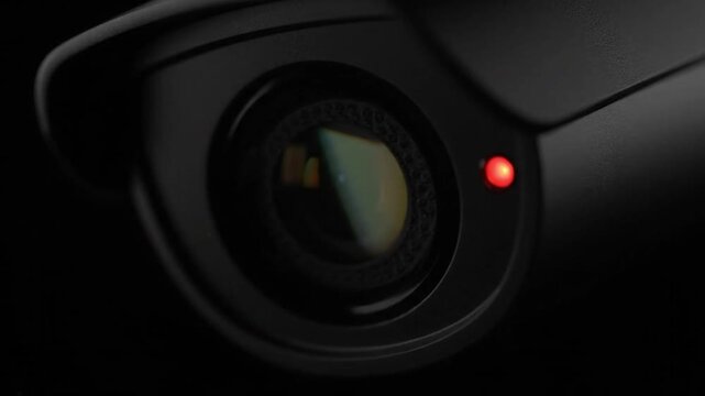 Security camera lens with glowing red indicator light close up