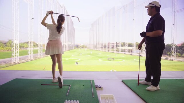 Professional golf coach teaching a beginner at driving range