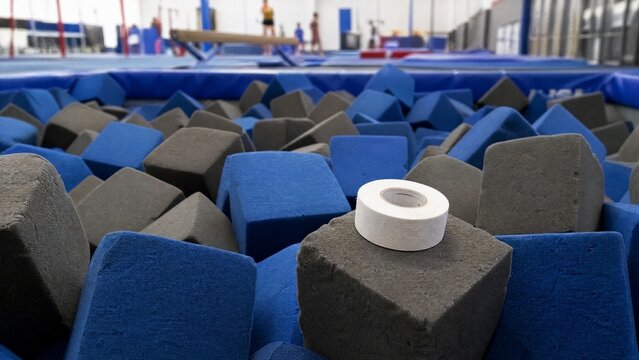 pit. A pile of soft foam cubes in a gymnasium pit with athletic tape on top. event key visuals, club posters, designed for sports event promotions and stadium branding, used by sports marketers.