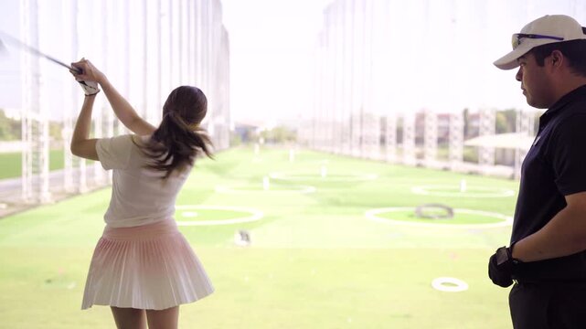 Professional golf coach teaching a beginner at driving range
