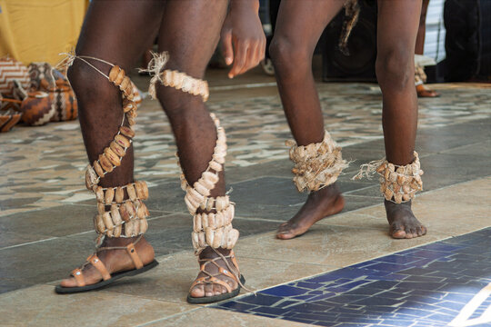 Traditional african dancers wearing leg rattles and woven ornaments during a performance