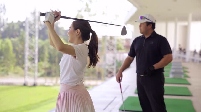 Professional golf coach teaching a beginner at driving range