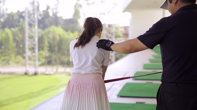 Professional golf coach teaching a beginner at driving range
