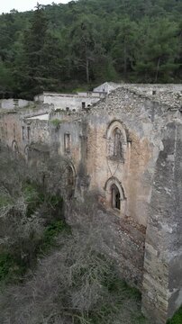Vertical drone aerial video of Saint Magar Monastery ruins in Northern Cyprus surrounded by mountains and Mediterranean nature.