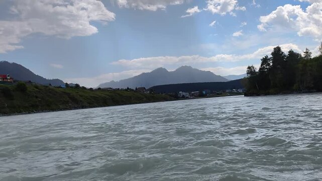 A motorboat ride along mountain river. Slow motion of speedboating on Altai river Katun. Mount Camel is in the background.