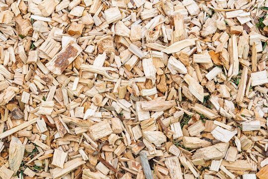 Close-up full frame view of a pile of wood chips, commonly used for landscaping, mulch, or biomass fuel. The chips vary in size and color, creating a textured and natural.