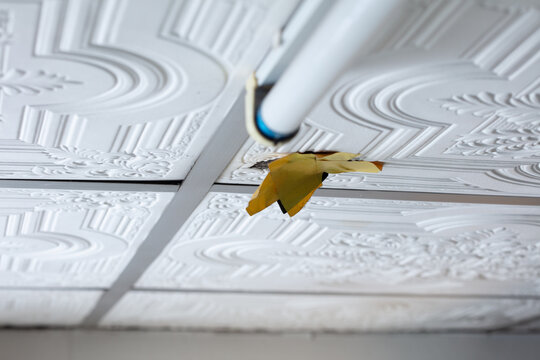 Dangerous ceiling water leak near fluorescent light inside house. Water leaking from damaged ceiling with electrical hazard indoors