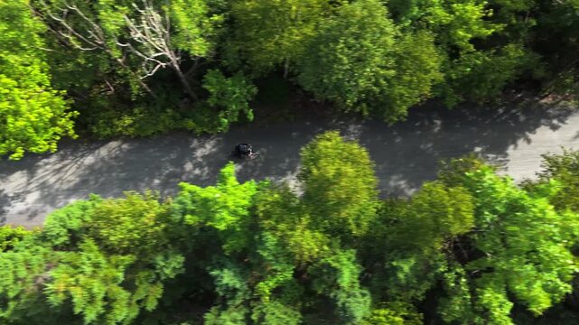 Drone aerial Top View cycling on gravel trail through forest near lake in Nova Scotia Canada. Summer scenery with active lifestyle and peaceful natural environment 
