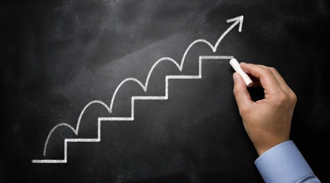 Hand drawing upward trending staircase graph with chalk on a blackboard, symbolizing growth, success, and progress