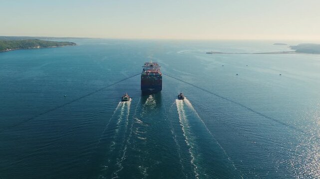 Cinematic drone shot Global Trade Container Ship Halifax Canada Aerial View Tugboats Escorting Vessel Early Morning Shipping Logistics And Maritime Transport 4K