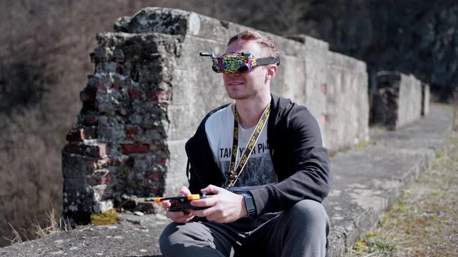 Man flies a drone outdoors using FPV goggles on a sunny day