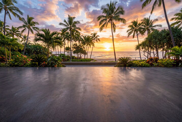 Fototapeta premium Empty dark grey concrete floor foreground against tropical beach sunset with tall palm trees