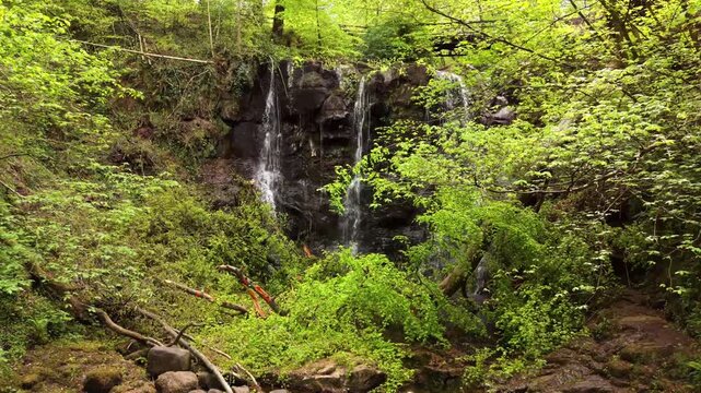 4K 60FPS aerial video of Glenariff Waterfall in County Antrim, Northern Ireland in the UK. Produced in 3840x2160 and with Rec709 color. Sunlight shines through the trees.