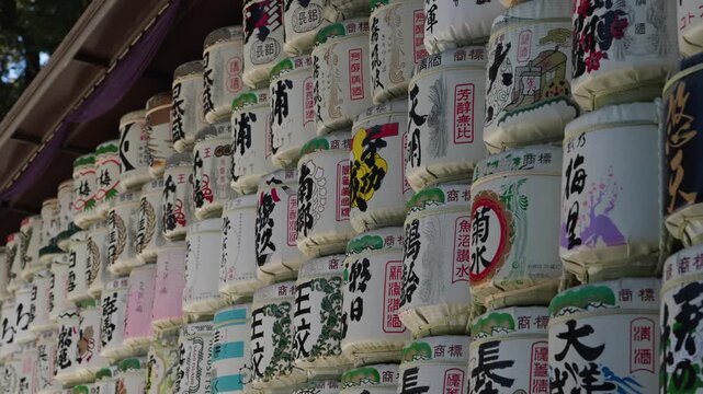 Closeup of stacked sake donation barrels with detailed kanji calligraphy and colorful painted labels Meiji Shrine Tokyo