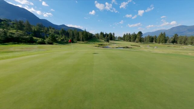 Red Flag Marking Hole On Green Fairway At Golf Course In Kootenay Rockies, BC, Canada. FPV drone shot
