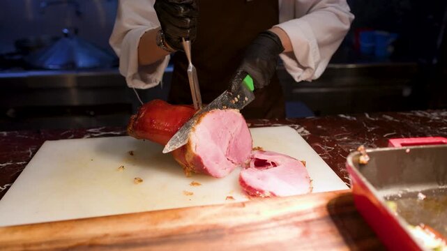 Professional Chef Slicing Roasted Ham with Carving Knife and Fork