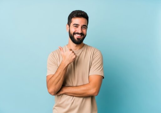 Happy young man with beard giving thumbs up gesture against blue background