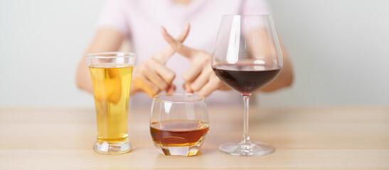 woman stop hand gesture to refuse a glass of wine, beer, whiskey or cognac on table. say no to...