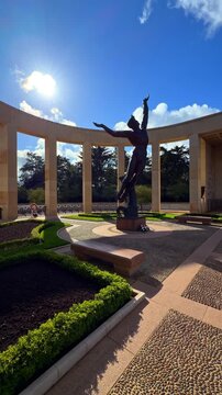 Slow pan across memorial monument with statue, stone columns and landscaped gardens