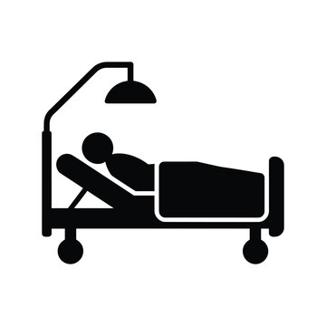 Medical hospital bed with patient lying down under overhead lamp