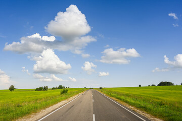 Fototapeta premium Empty highway with green field and white clouds on a summer day, Oryol region of Russia