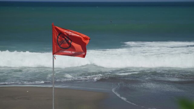 Red warning flag on a beach indicating dangerous ocean conditions and no swimming.