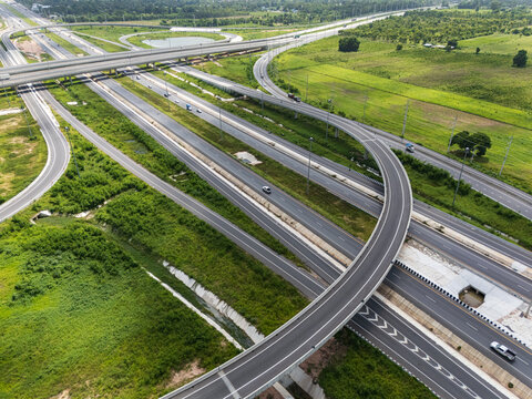 Drone shot a large highway interchange crossing over green farmlands in Thailand