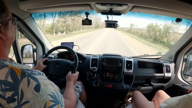 Adult couple on road trip in campervan driving on highway on sunny day