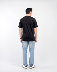 Fototapeta premium Male body wearing black t-shirt and blue jeans seen from behind and isolated on white background