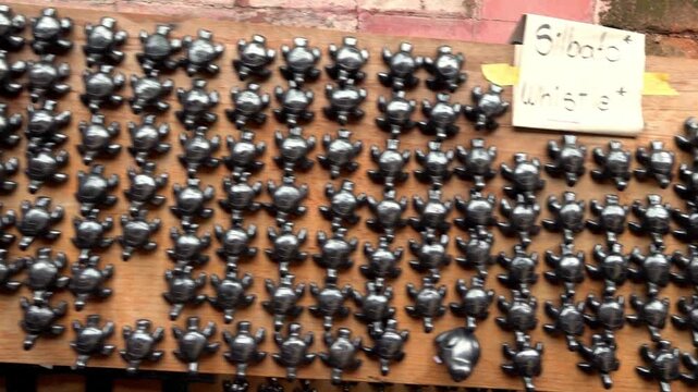 Collection of handcrafted turtle figurines displayed in organized rows on wooden table inside traditional artisan market in Mexico