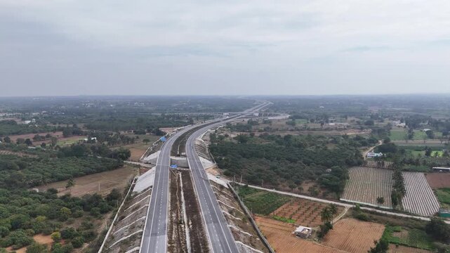 Drone shot capturing the Chennai&ndash;Bengaluru Expressway winding through agricultural terrain, featuring long elevated sections, geometric road patterns, and expansive countryside scenery.