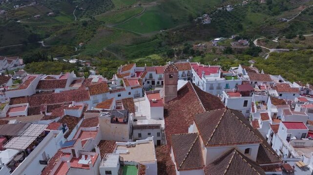 Drone footage of Frigiliana, Andalusia, Spain, showing a descending approach toward the village church with whitewashed homes and mountain scenery in the background.