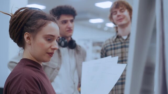 Two curly-haired male students and their dreadlocked female partner work together to solve a challenging algebraic problem. 