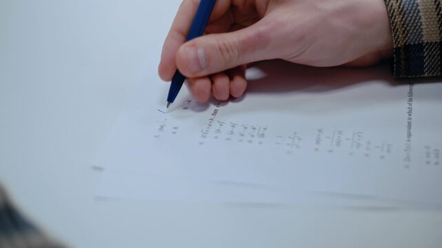 Close-up view of a pupil's hand holding a pen and taking a multiple-choice mathematics test